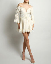 Ivory corset dress featuring a romantic empire cut-off shoulder top with full sleeves trimmed with lace. Available in black.
