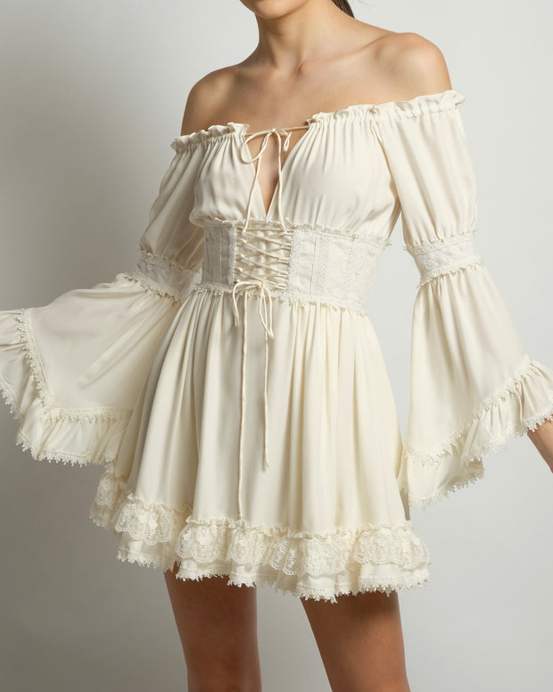 Ivory corset dress featuring a romantic empire cut-off shoulder top with full sleeves trimmed with lace. Available in black.